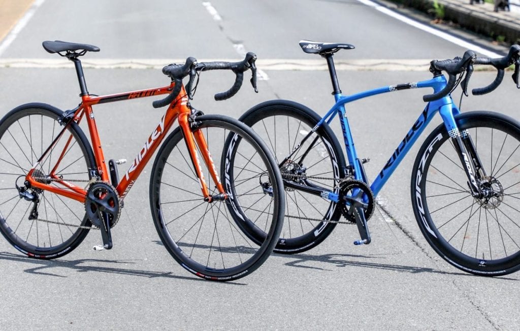 2020年メタリックオレンジカラーが追加になった軽量バイクHELIUM X(左)と、新たにラインナップに名を連ねるグラベル"レーシング"バイクのKANZO SPEED(右)